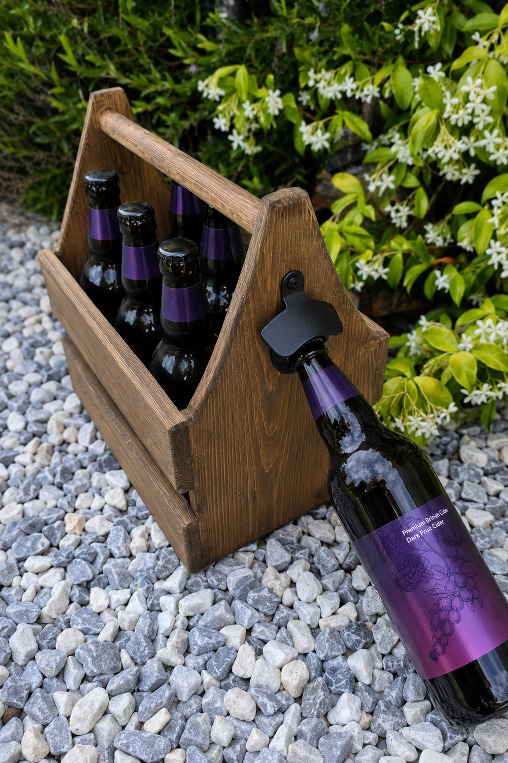 Wooden bottle carrier with wine bottles on a gravel surface with greenery in the background